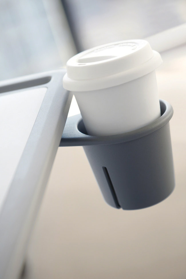 Nahaufnahme eines integrierten Getränkehalters an einem Lehrtisch – innerhalb der Halterung befindet sich ein weißer Kaffeebecher