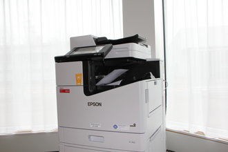 Einzelner EPSON Drucker in einem hellen Büroraum vor zwei Fenstern.