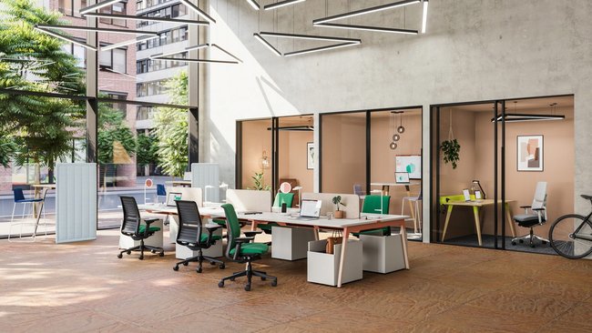 Großer offener Arbeitsraum mit Glasfront auf der linken Seite und einer Wand mit kleinen, durch Glasscheiben sichtbare Bürozimmer. In der mitte des großen Saals sind Tische mit Laptops und Bürostühlen platziert, die gemeinsam insgesamt sechs Arbeitsplätze bilden.