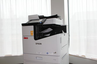 Einzelner EPSON Drucker in einem hellen Büroraum vor zwei Fenstern.